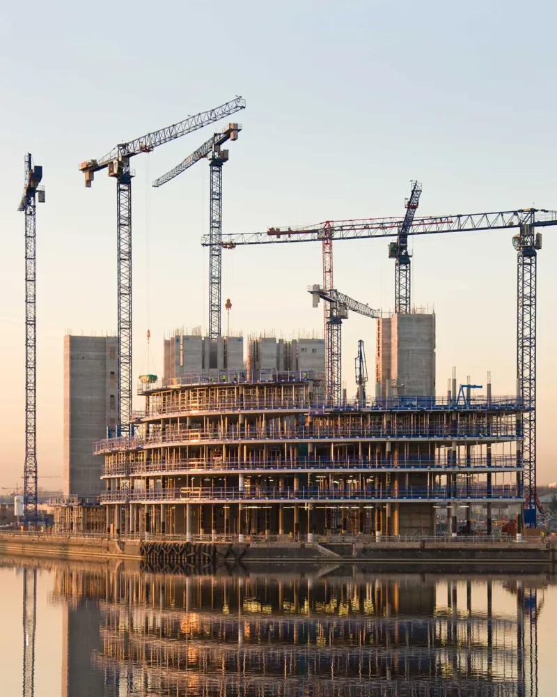 Grúas de construcción en un edificio de oficinas junto al agua